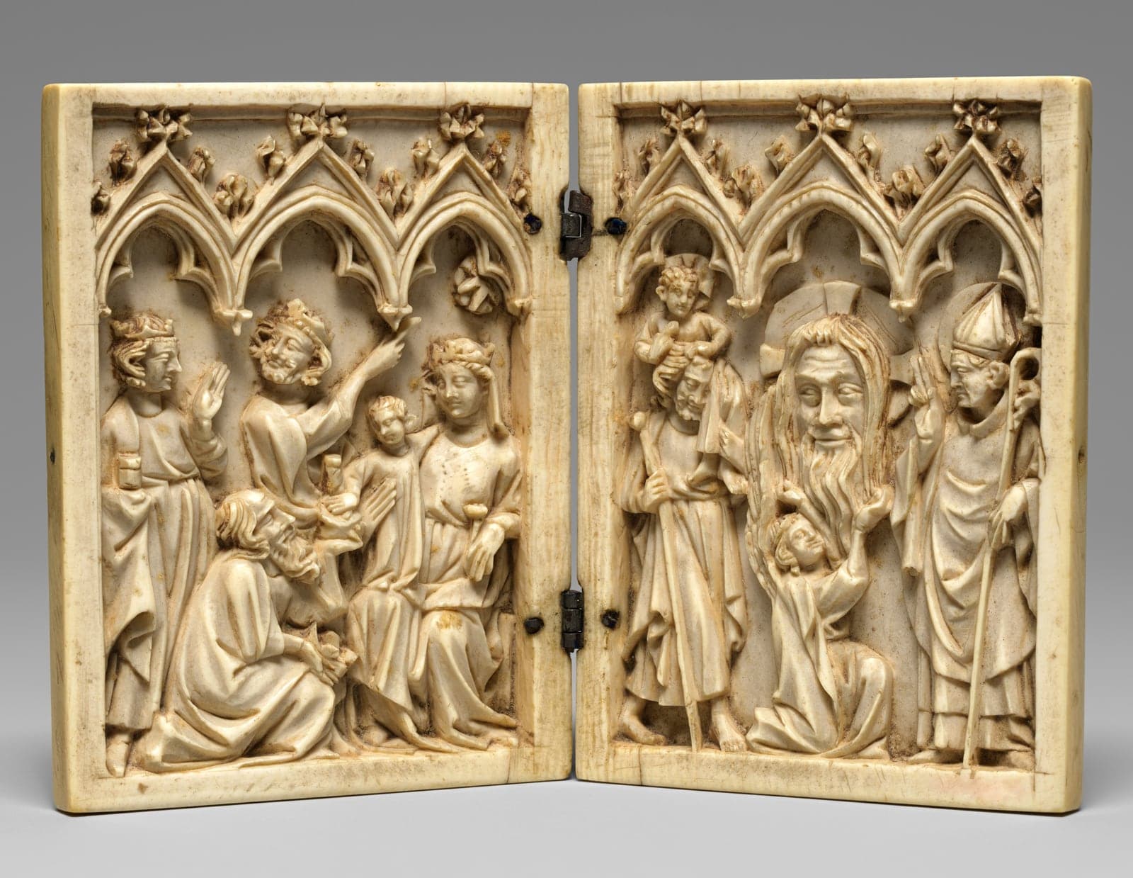 A small hinged ivory panel carved with three crowned kings kneeling before the Virgin and Child beneath Gothic arches.